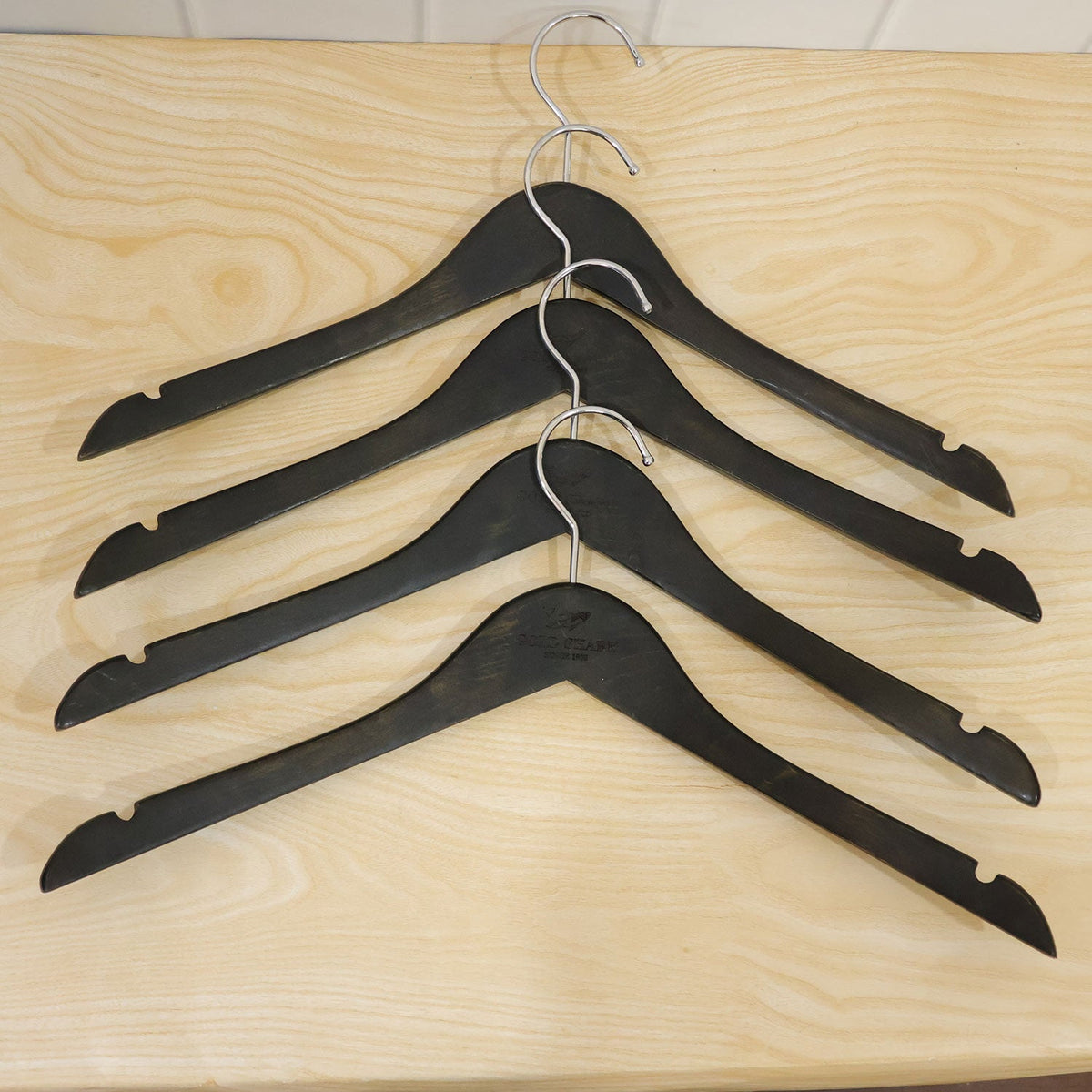 Set of four Wukusy premium clothes hangers with metal hooks for wardrobe storage, showcasing sleek and sturdy design.