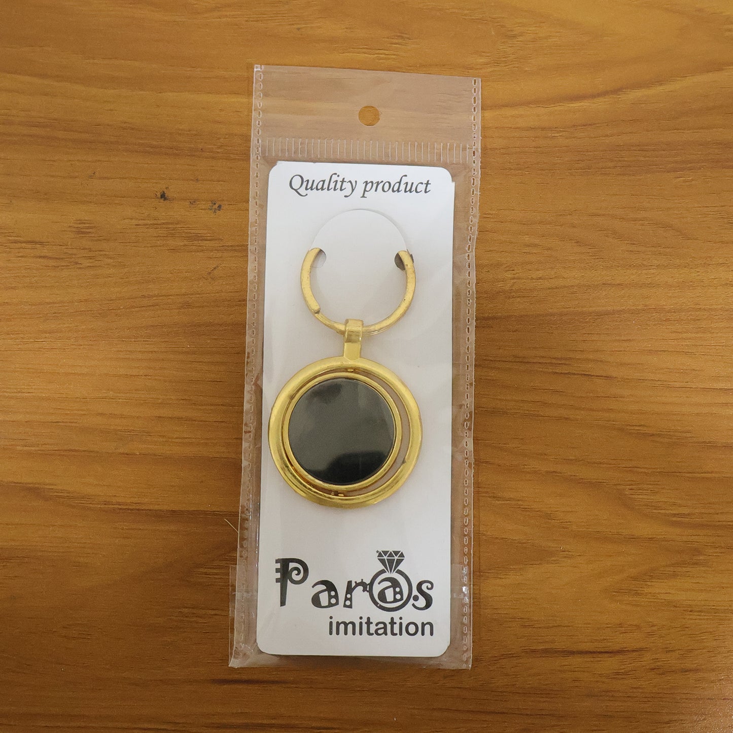 Gold plated keychain with black round rotating pendant, featuring a sleek design and Wukusy branding, on a keyring.