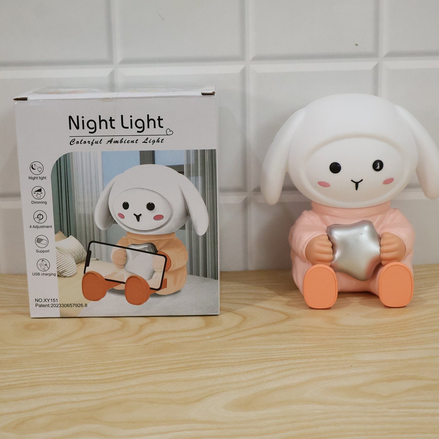 Wukusy rabbit LED night light with mobile phone stand on bedroom or study table, providing soft lighting and convenient device support.
