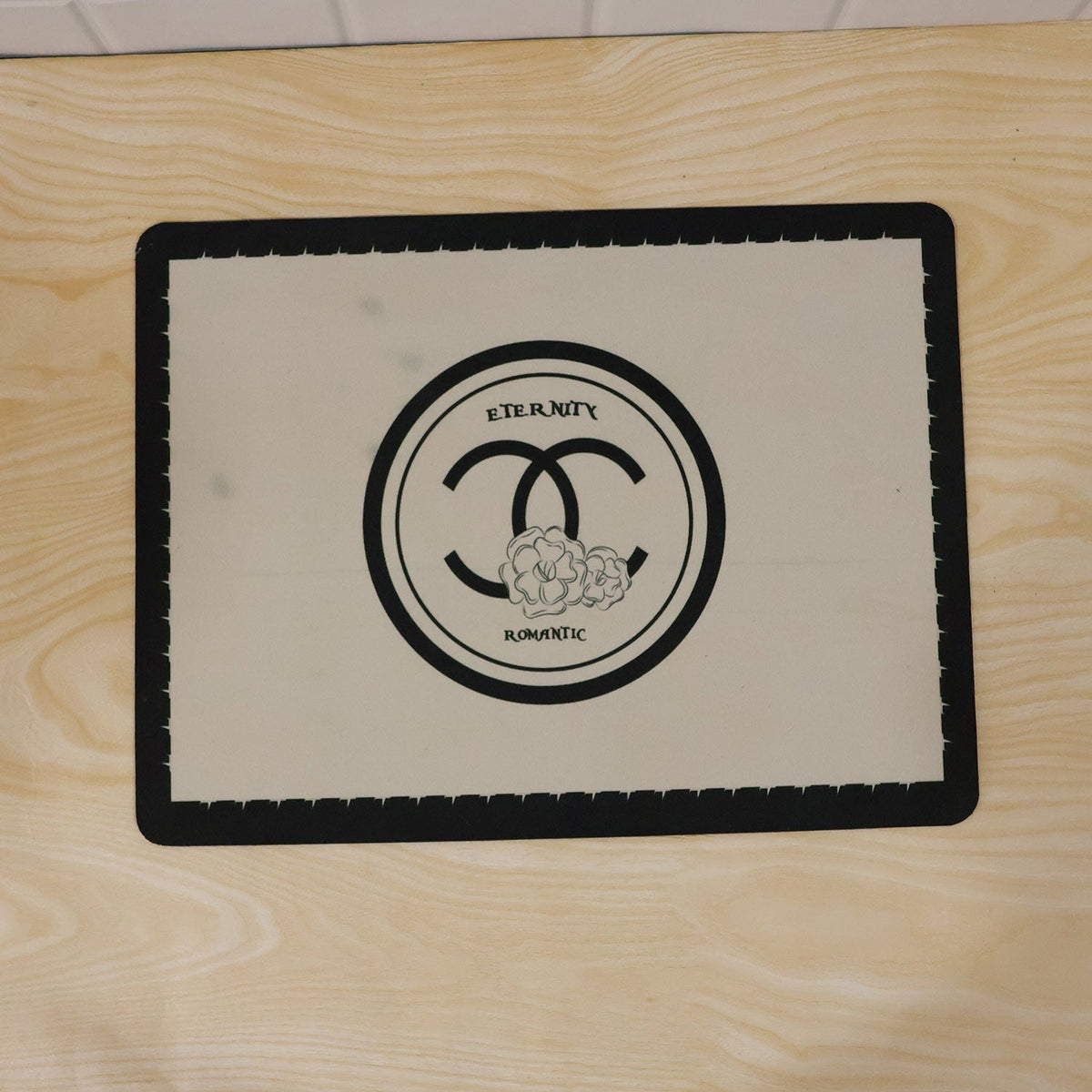 Black and cream Wukusy bath mat with soft, textured, absorbent surface, measuring 40x30 cm, placed on a bathroom floor.