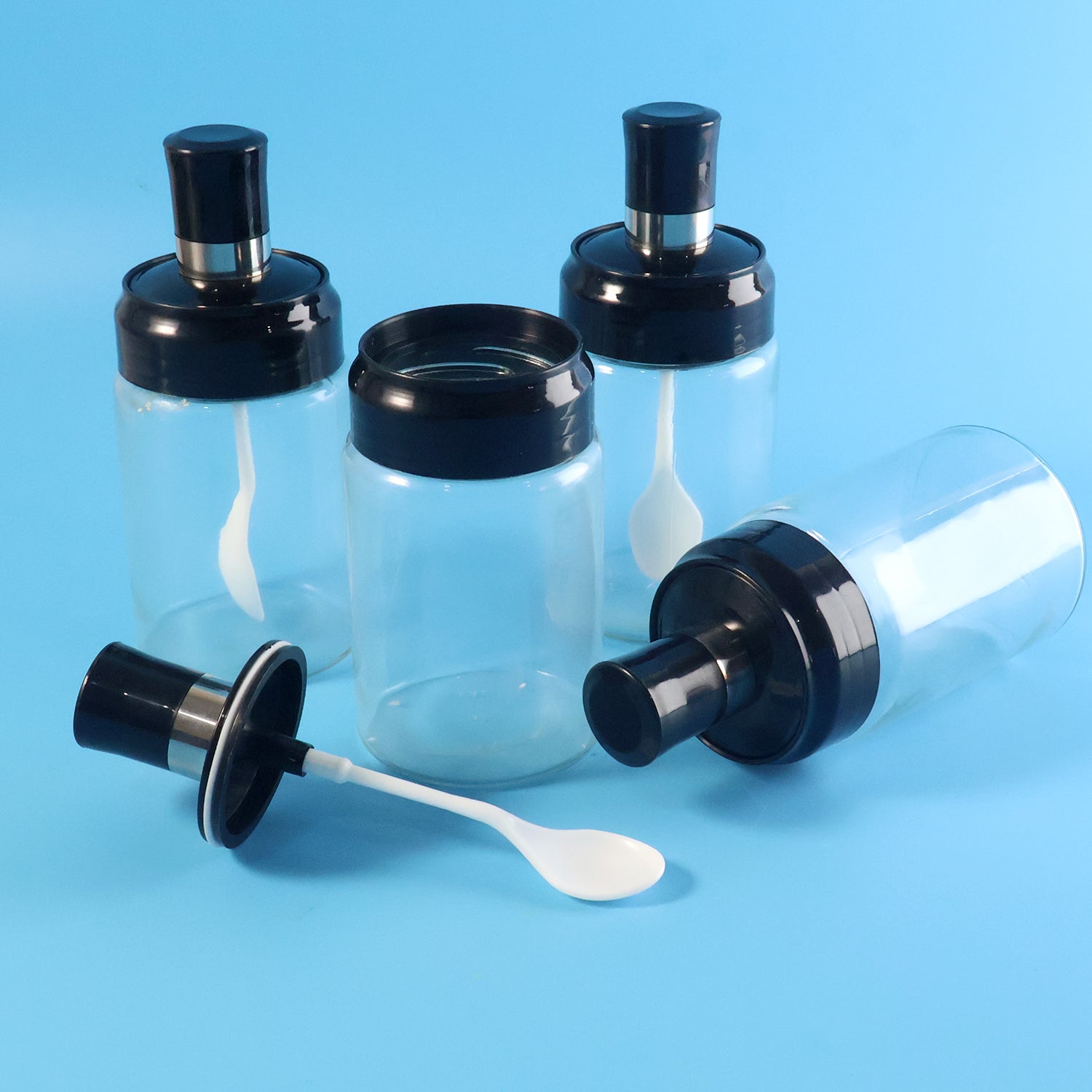 Set of four transparent spice jars with airtight lids and spoons by Wukusy for storing herbs and spices in the kitchen.