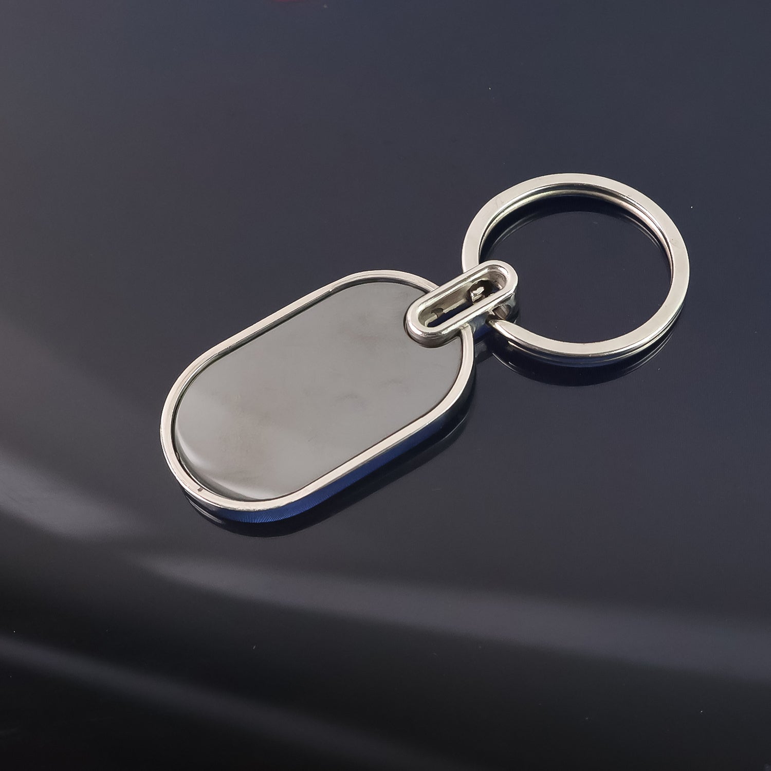 Elegant black and silver oval metal keychain by Wukusy with a sleek, polished finish and a sturdy keyring attachment.