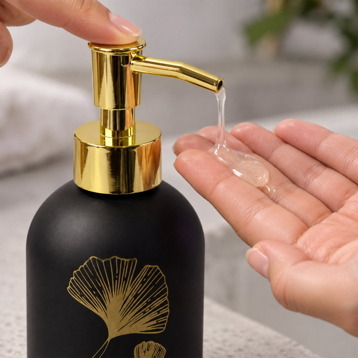Wukusy manual liquid soap dispenser with leaf design and refillable pump bottle, shown on a bathroom countertop.