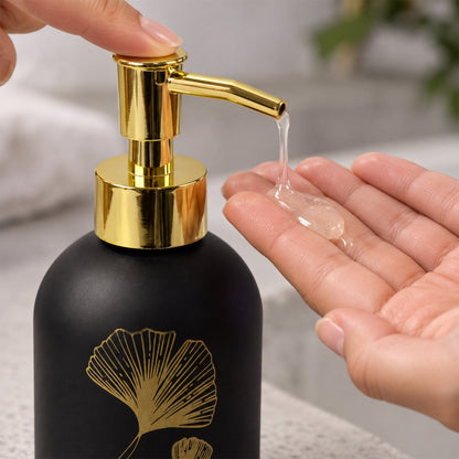 Wukusy manual liquid soap dispenser with leaf design and refillable pump bottle, shown on a bathroom countertop.