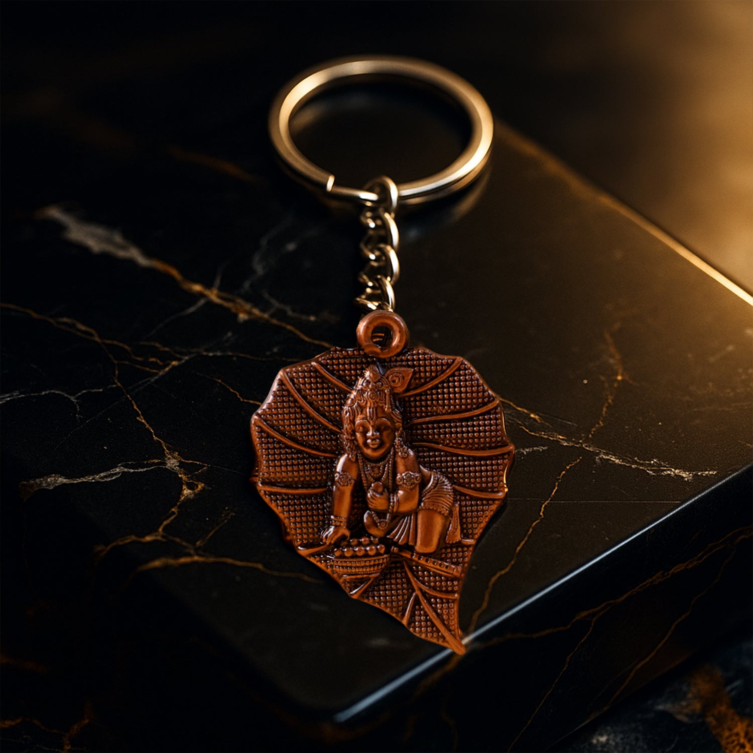 Antique-finish metal keychain from Wukusy with intricate design and polished surface, displayed on a neutral background.