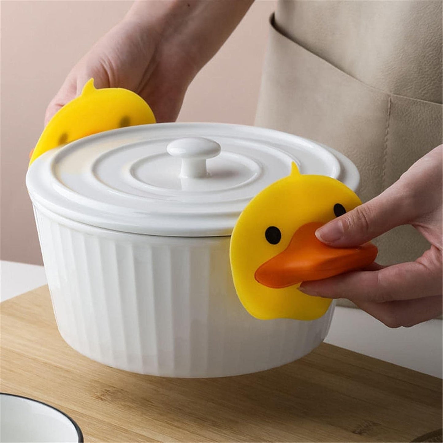 Pair of Wukusy duck-shaped silicone hot pot holders featuring cute yellow duck designs for safe handling of hot cookware.