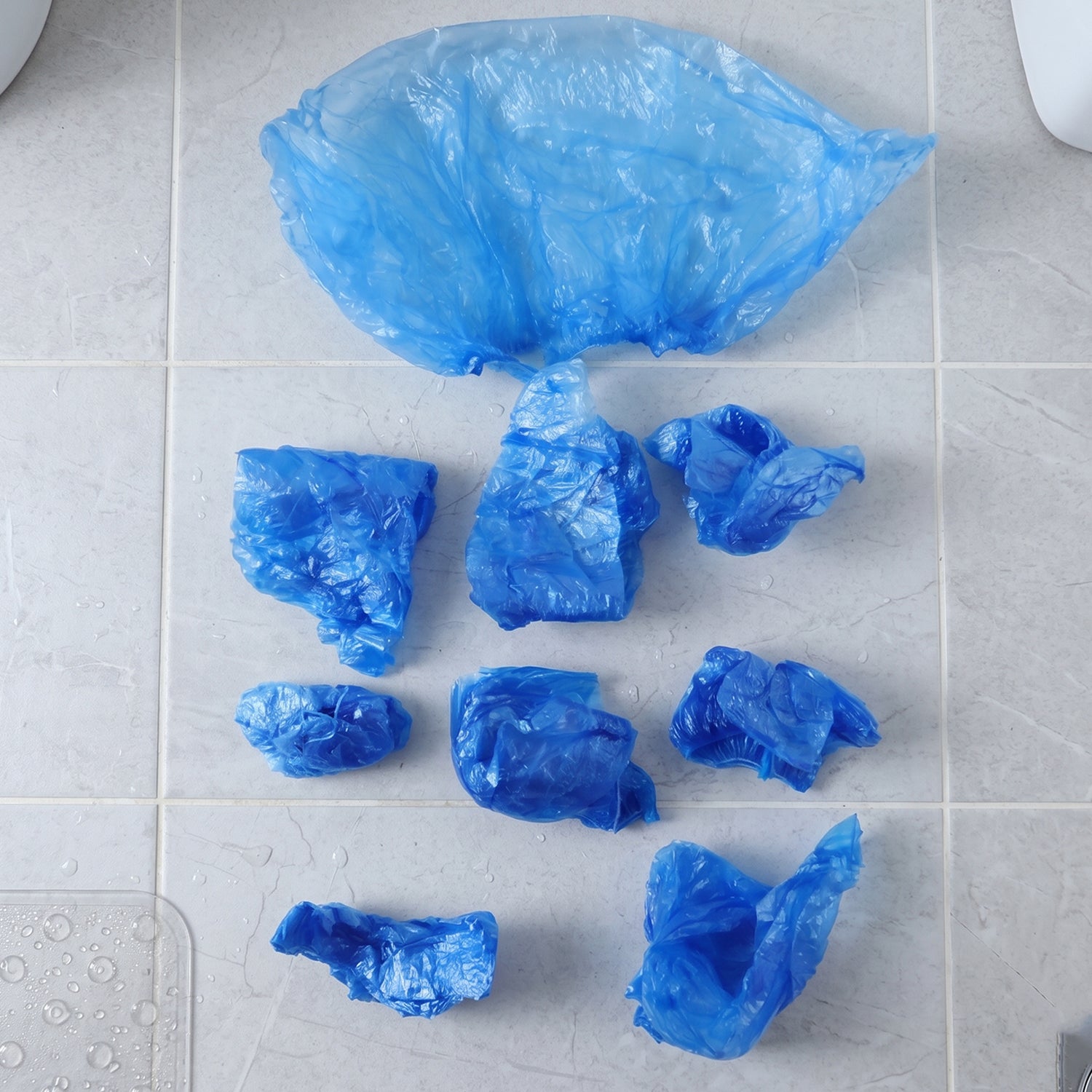 Wukusy disposable plastic shoe covers with elastic fit, shown in a set of 100, protecting shoes during cleaning or medical tasks.