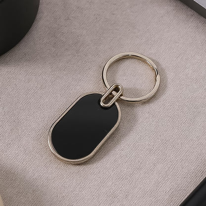 Elegant black and silver oval metal keychain by Wukusy, featuring a sleek design and sturdy keyring.