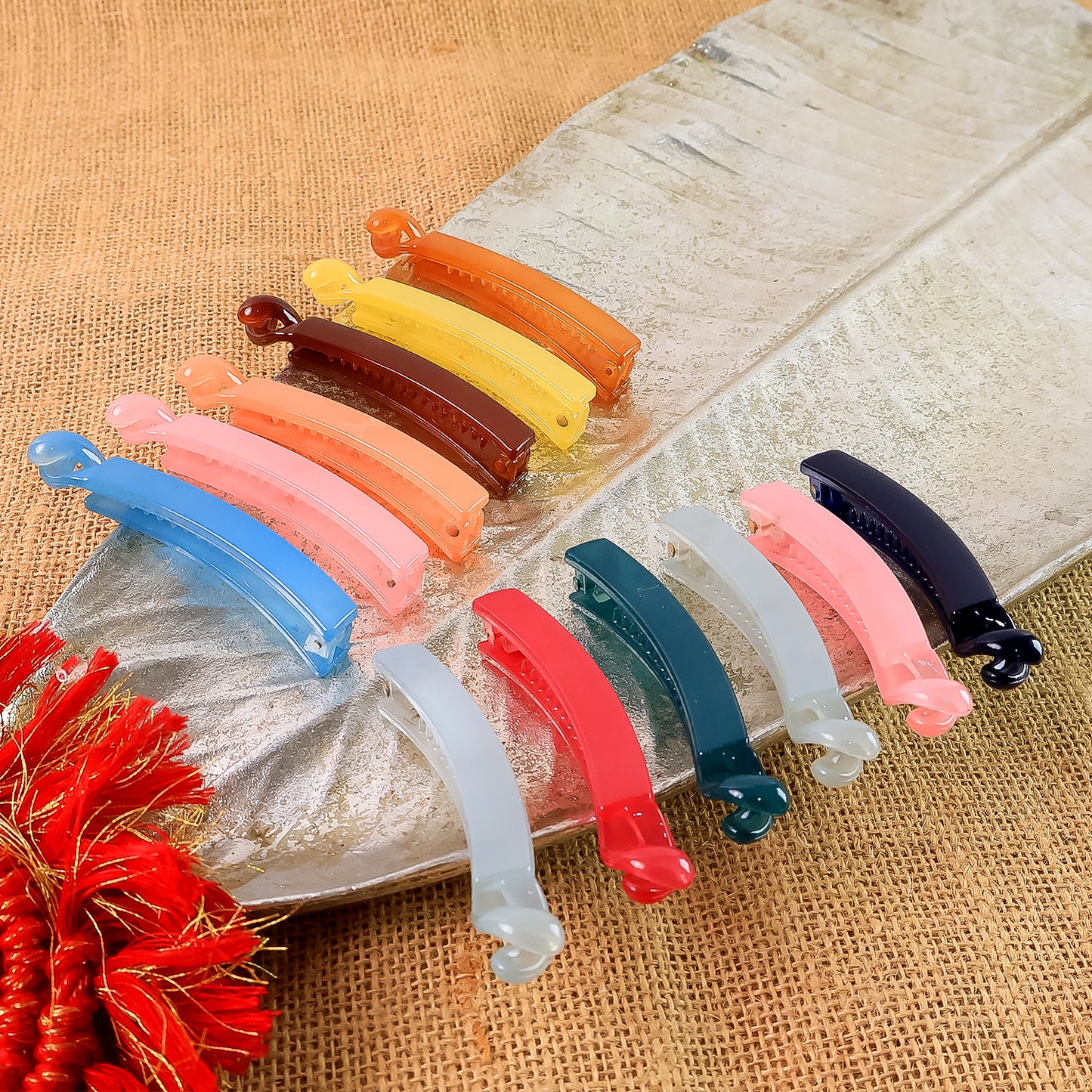 Set of 12 multicolor plastic banana-shaped hair clips by Wukusy, arranged in a colorful variety on a white background.