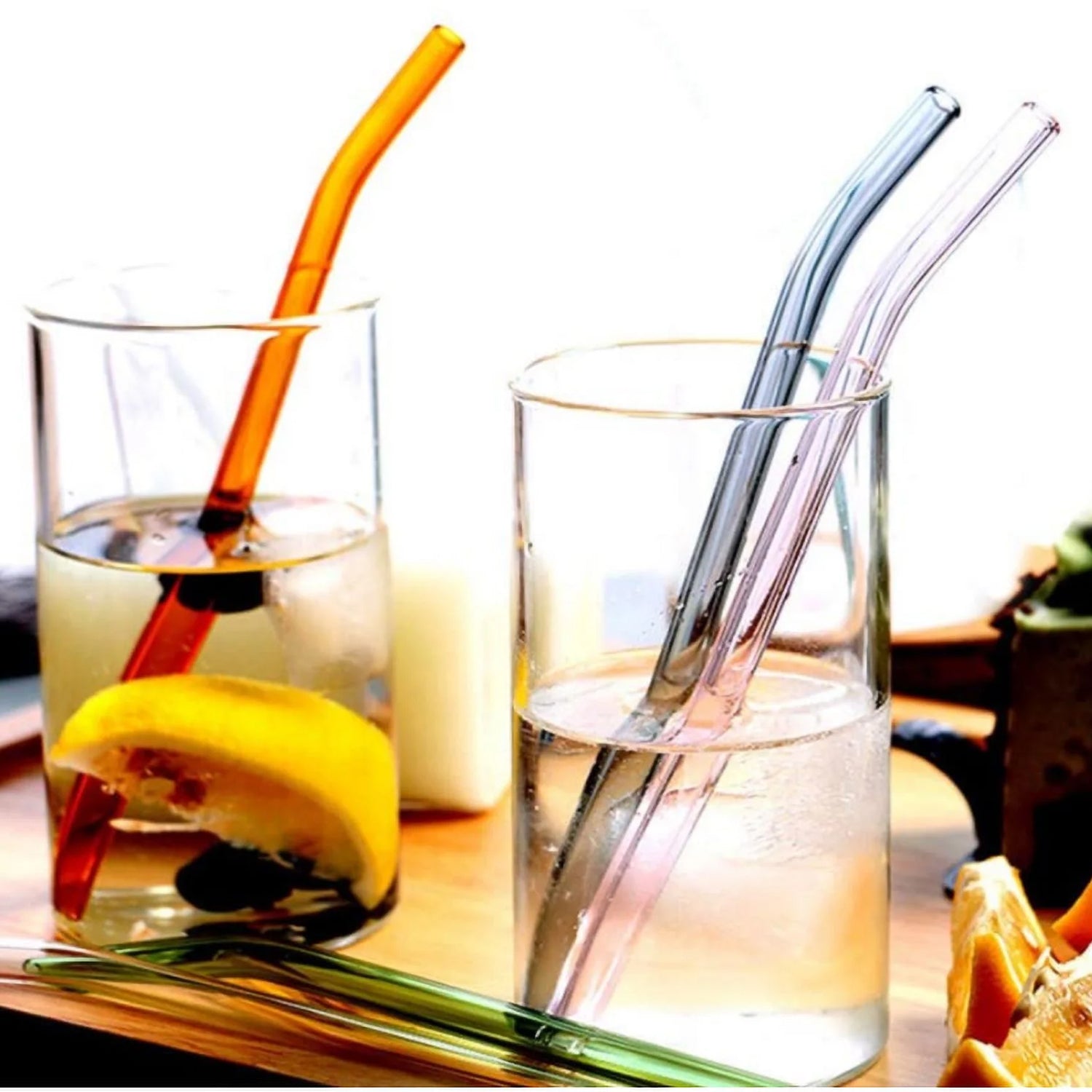 Set of five clear Wukusy reusable glass drinking straws on a kitchen countertop. Durable, eco-friendly glass straws for beverages.
