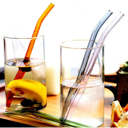 Set of five clear Wukusy reusable glass drinking straws on a kitchen countertop. Durable, eco-friendly glass straws for beverages.