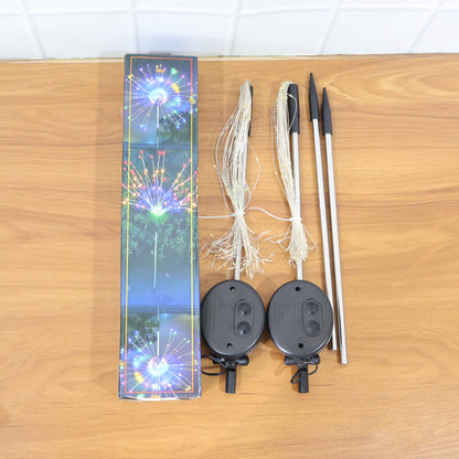 Wukusy solar-powered warm white starburst firework garden lights, 2-piece set with 120 LED bulbs, illuminating outdoor space at night.