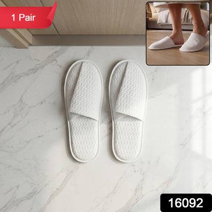Pair of white disposable hotel slippers for guests by Wukusy, soft fabric and comfortable fit, perfect for hotel stays.