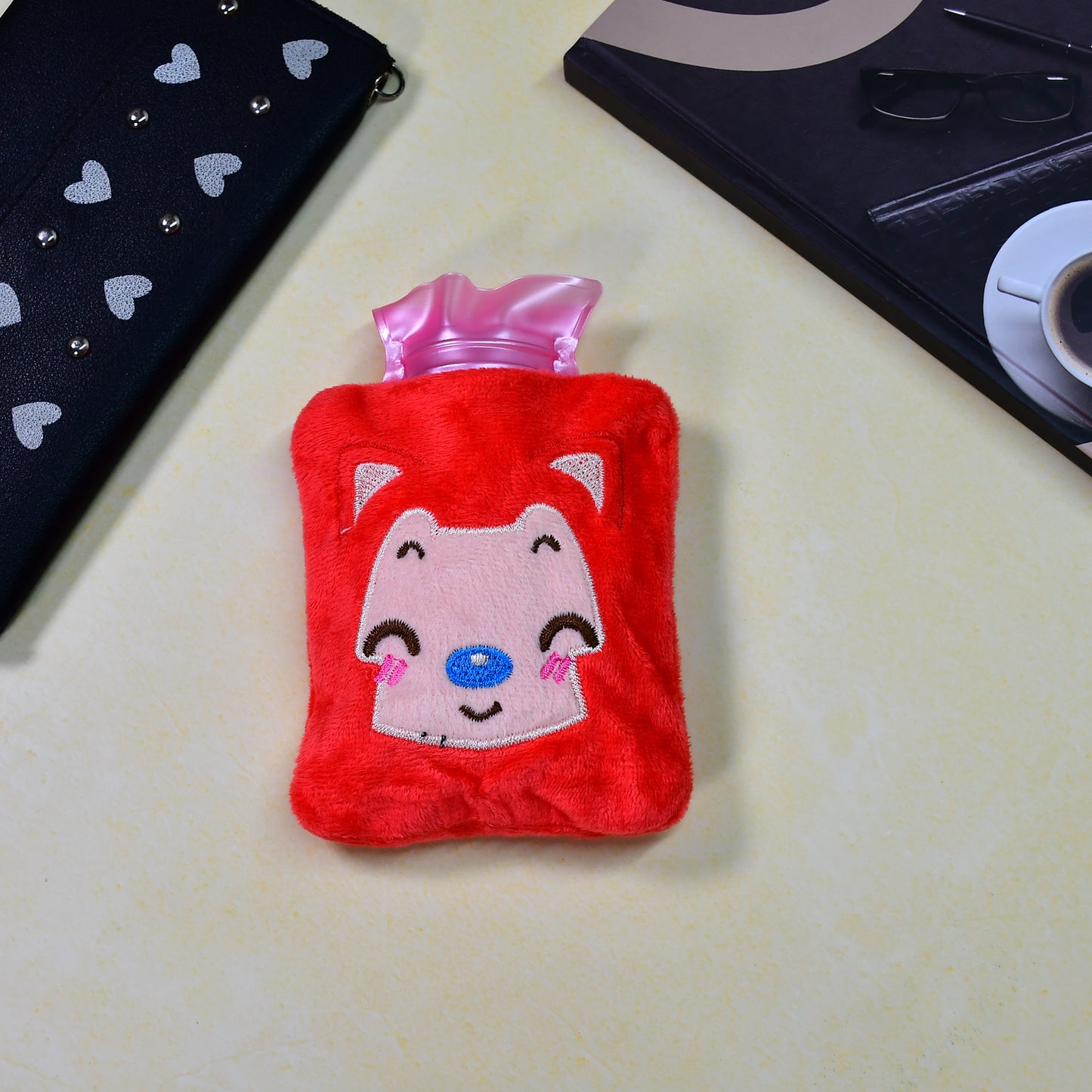 Pink cat-shaped Wukusy hot water bag with cover, used for pain relief, neck, shoulder, hand, feet warming, and menstrual cramps.