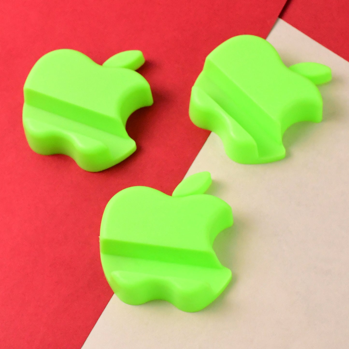 Set of three colorful Wukusy apple-shaped plastic mobile phone holders, ideal for desk or bedside use.